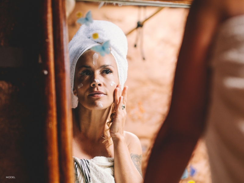 Woman applying a peptide serum to her face as part of a physician-recommended anti-aging skincare routine.